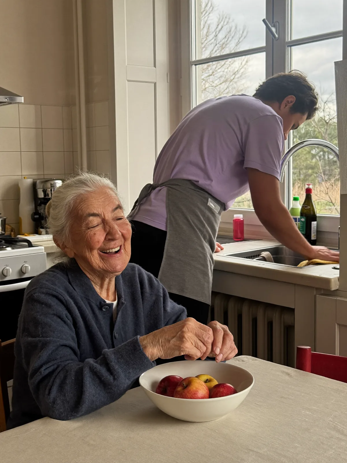 Haushaltshilfe und Seniorin in der Küche, beide lachen