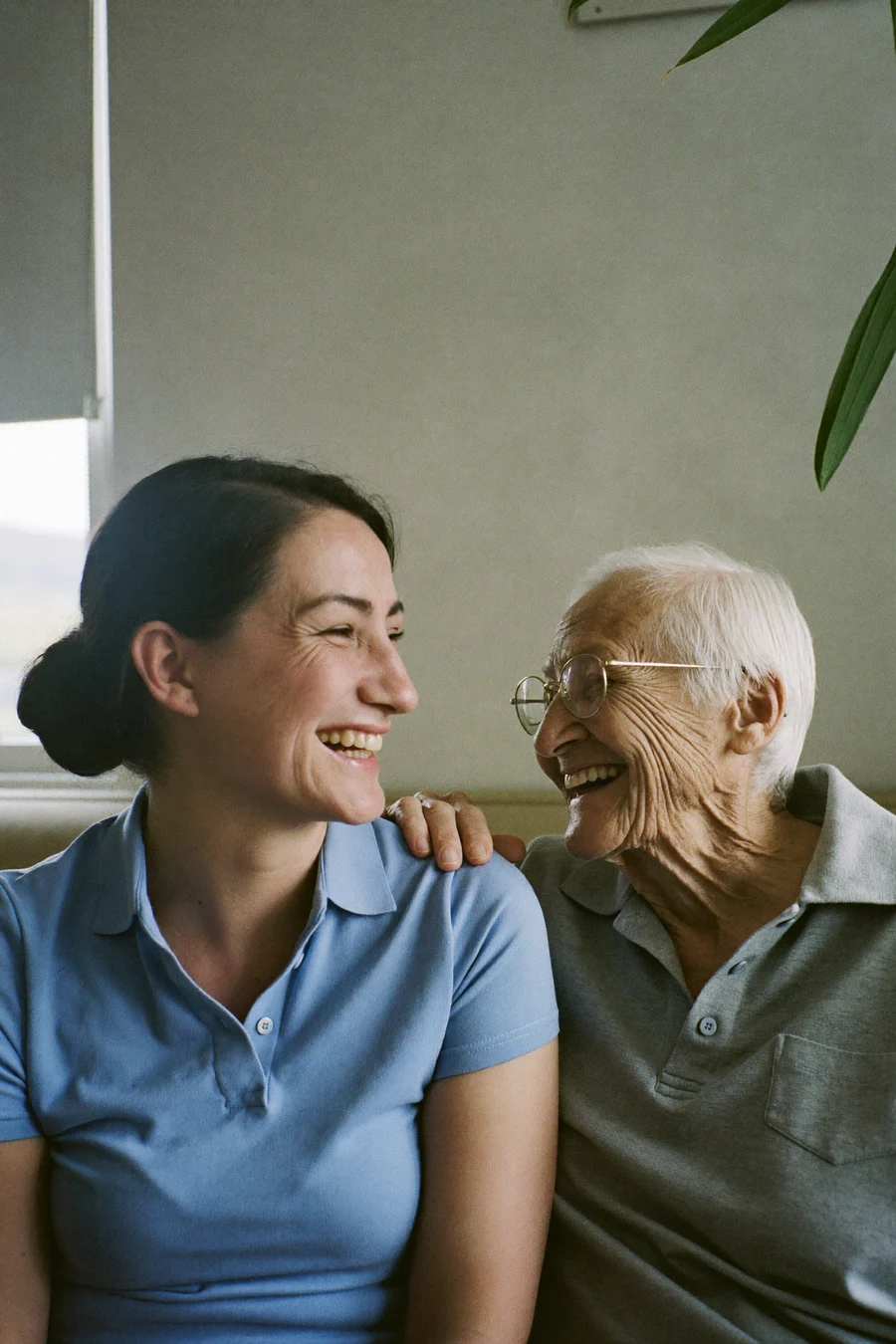 Haushaltshilfe von FamiliaPlus und eine Seniorin lachen gemeinsam